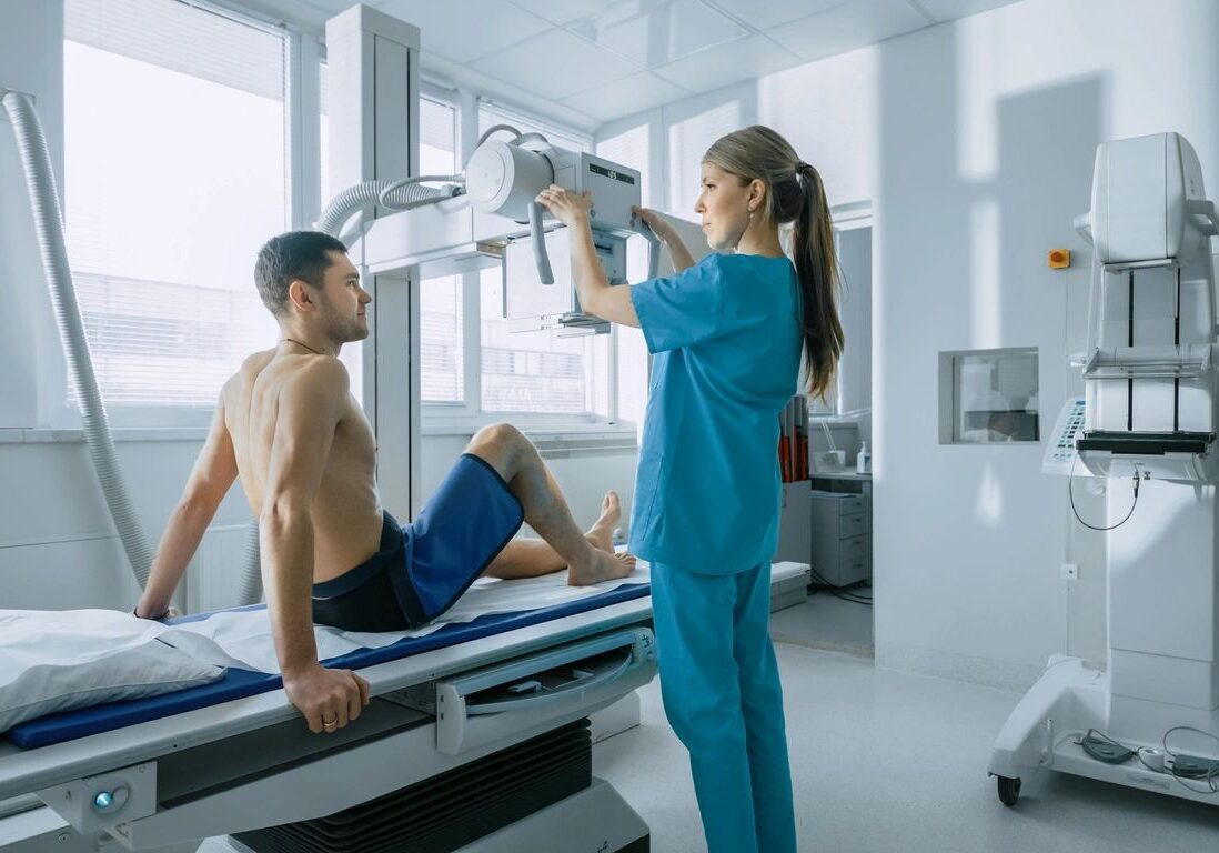 A woman in blue scrubs is holding up an x-ray.